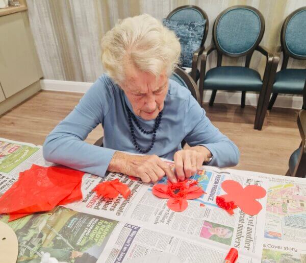 Lady at table doing Remembrance Day crafts